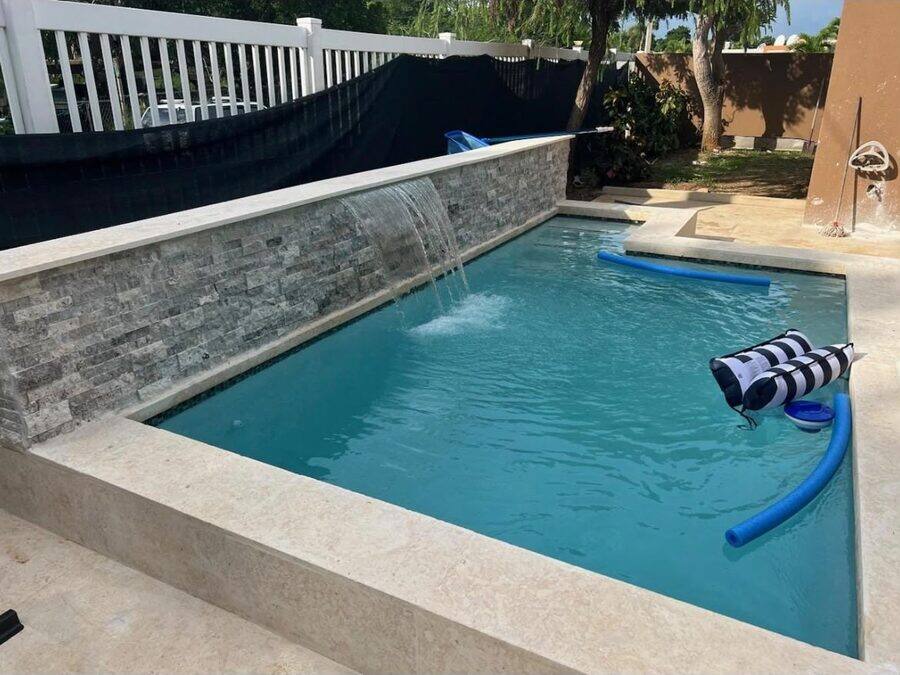 Velo de agua laminar cayendo sobre muro enchapado en piedra