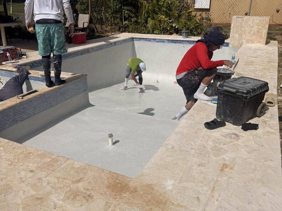 Cuadrilla aplicando el acabado interior de la piscina