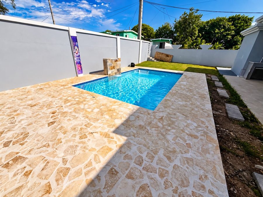 Piscina con cascada decorativa y aceras en coralina
